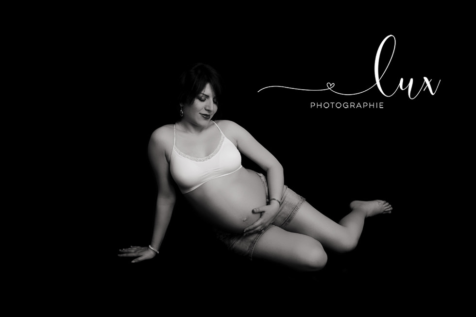 West-Island pregnancy photography. Pregnant woman sitting on the floor and holding belly.