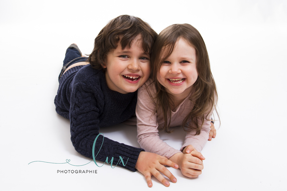 Montreal Children's Photographer. Brother and sister lying on the ground laughing.