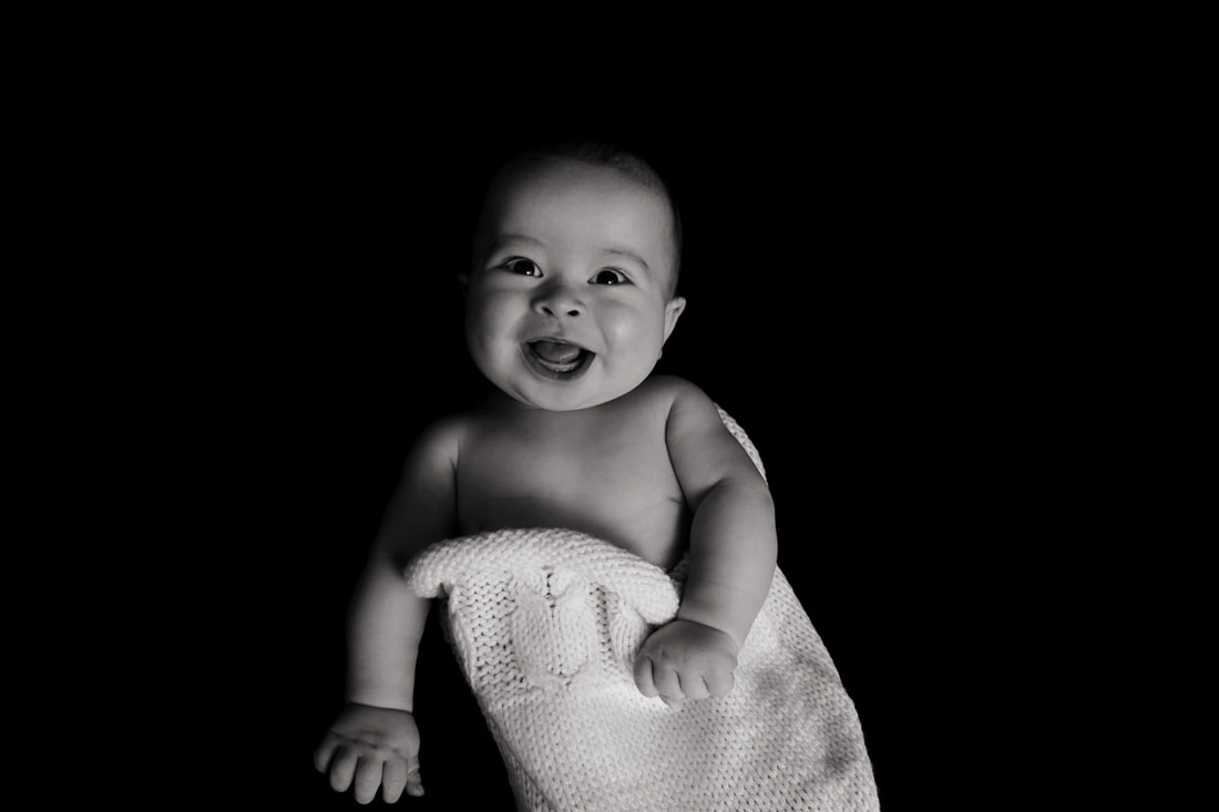 Baby smiling in a knitted sack