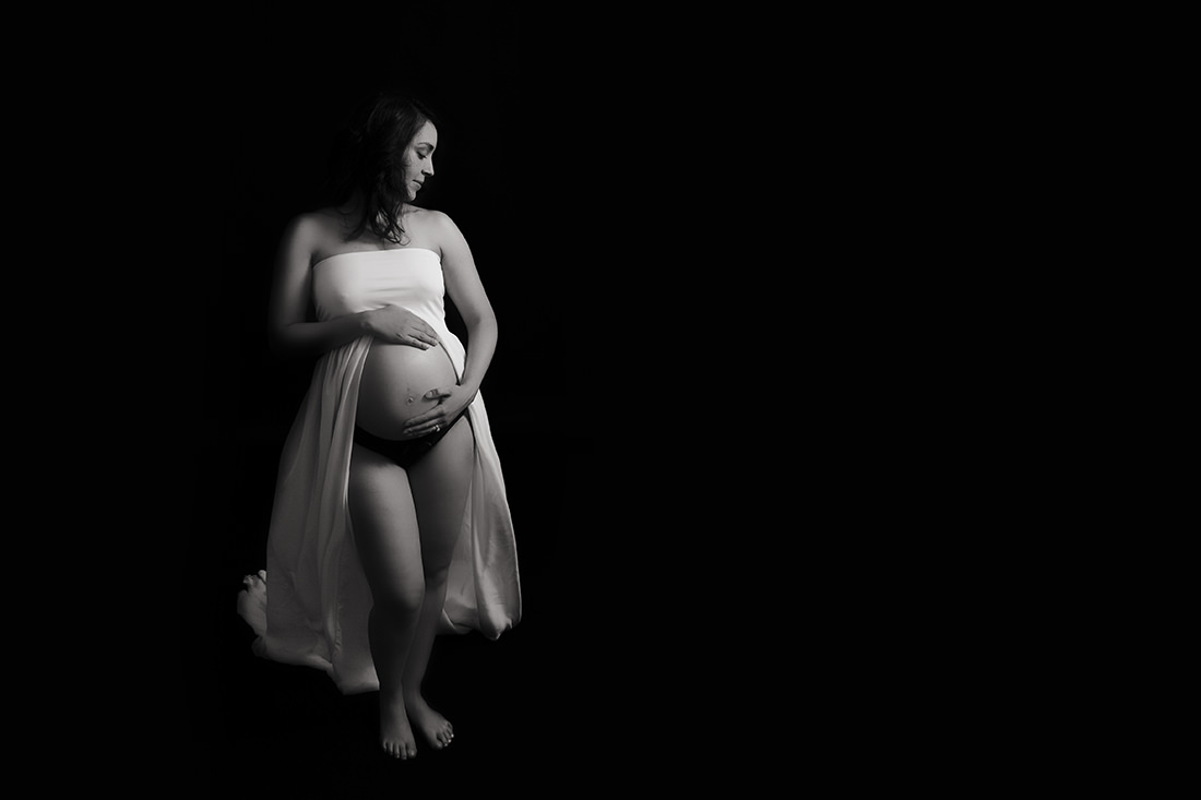 Pregnant woman holding belly in white gown montreal maternity photography