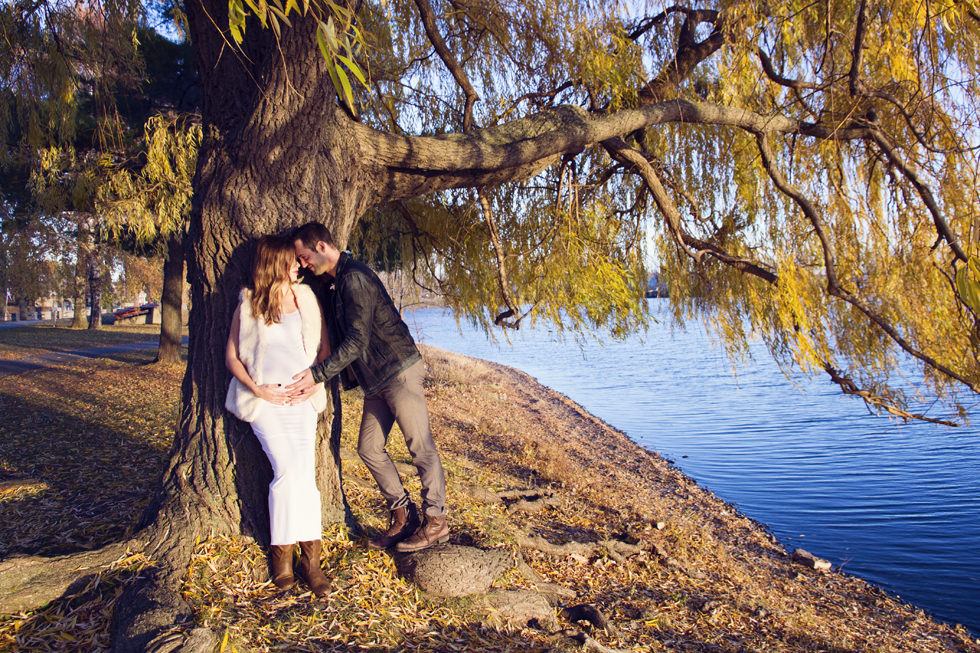 Montreal Maternity Photography. Man and pregnant woman kissing while leaning against tree.