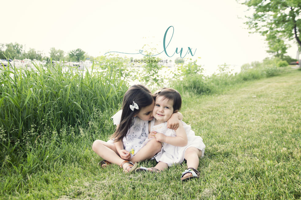 Montreal family photographer. Sisters sitting in the grass.