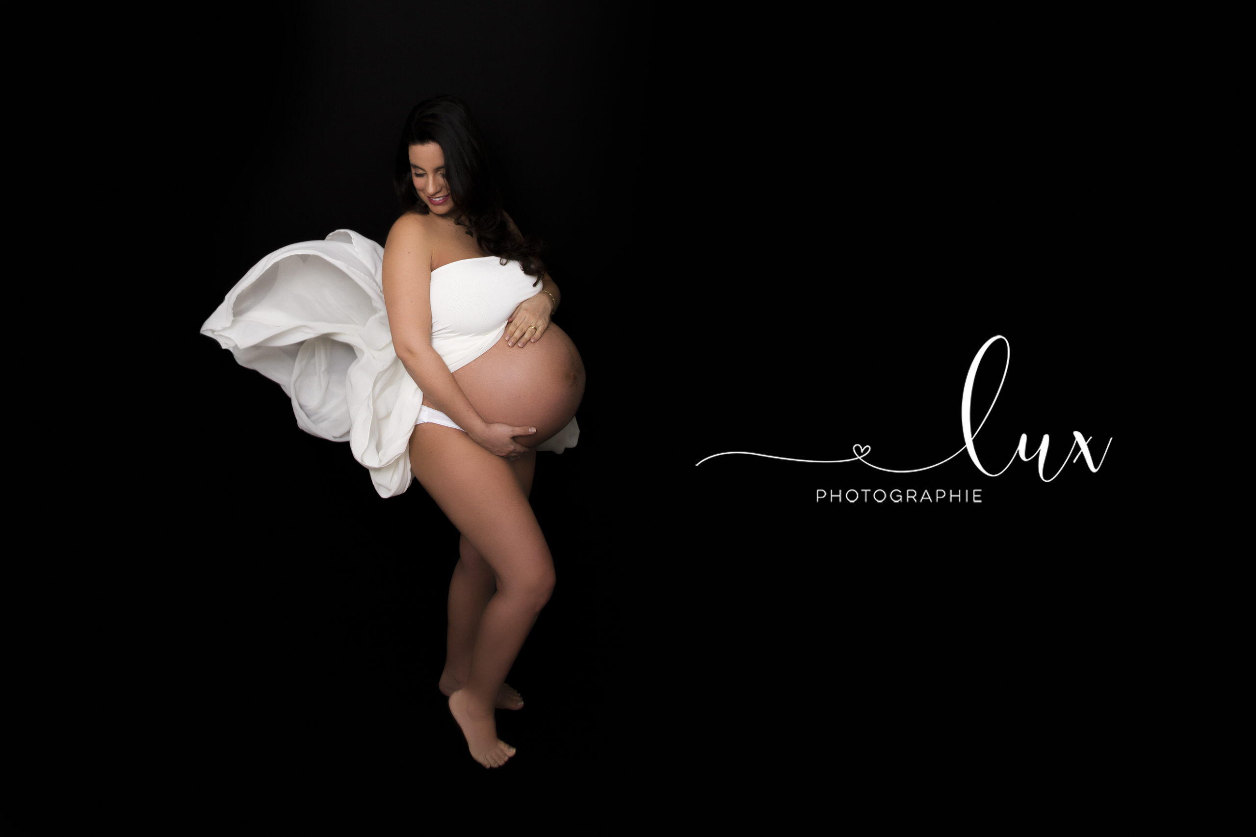 Montreal Maternity Photography. Pregnant woman in flowing white gown looking to the side.