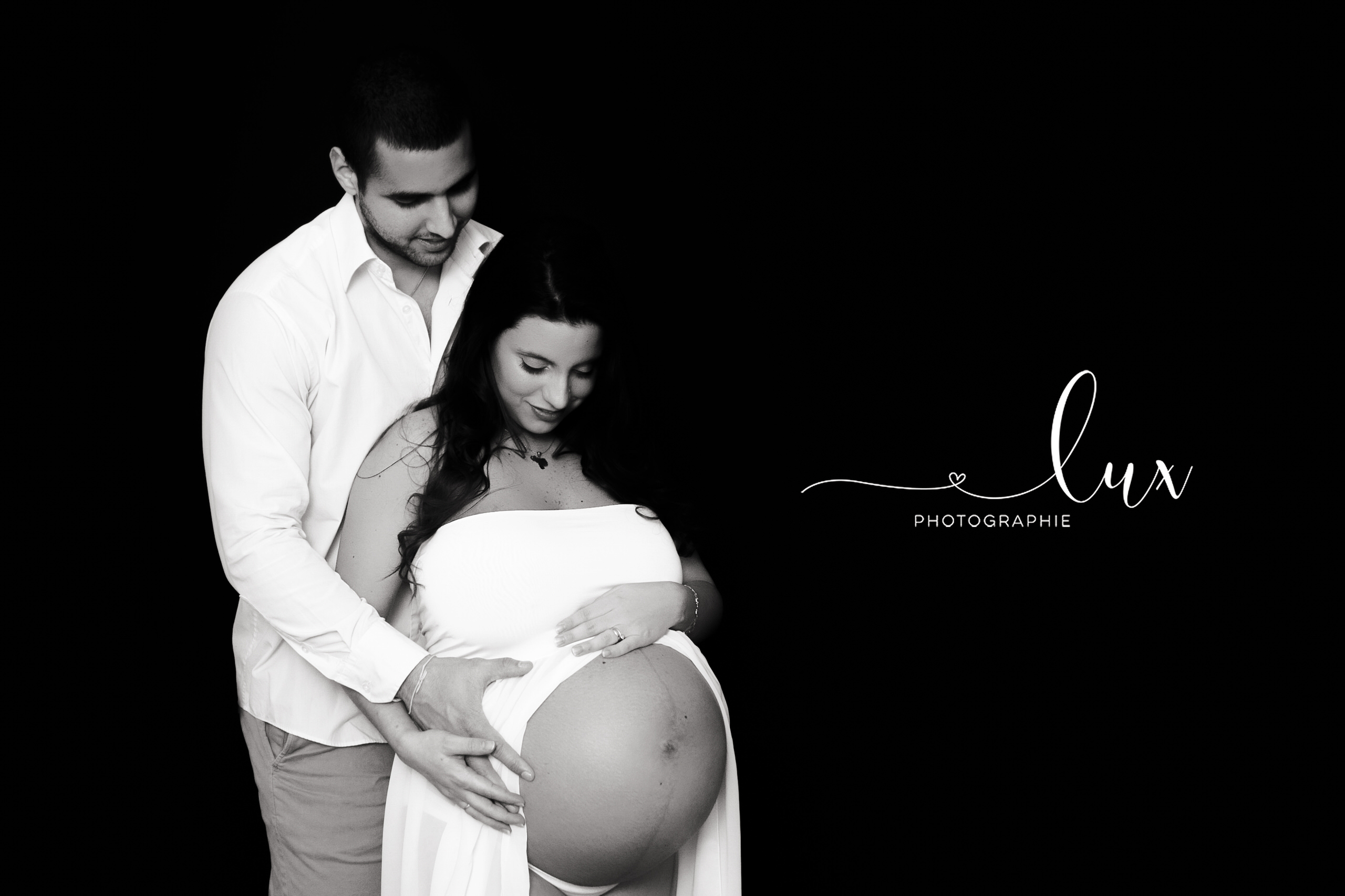 Montreal Maternity Photography. Man and pregnant woman looking down at woman's pregnant belly.