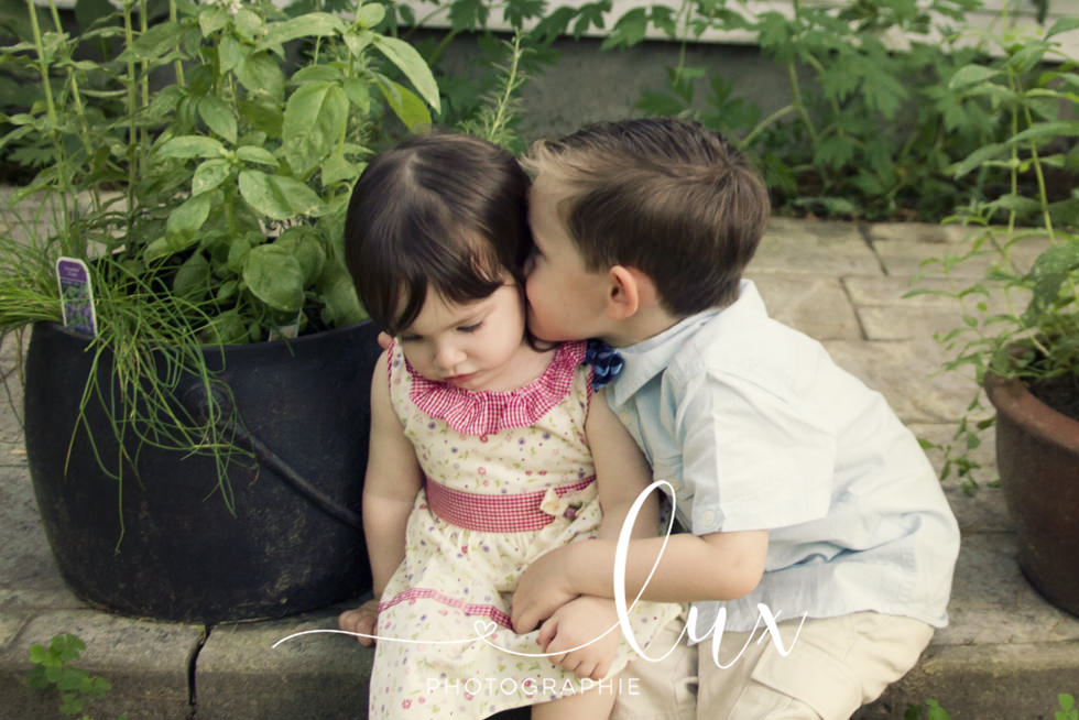 Family photography. Little boy kissing little sister.