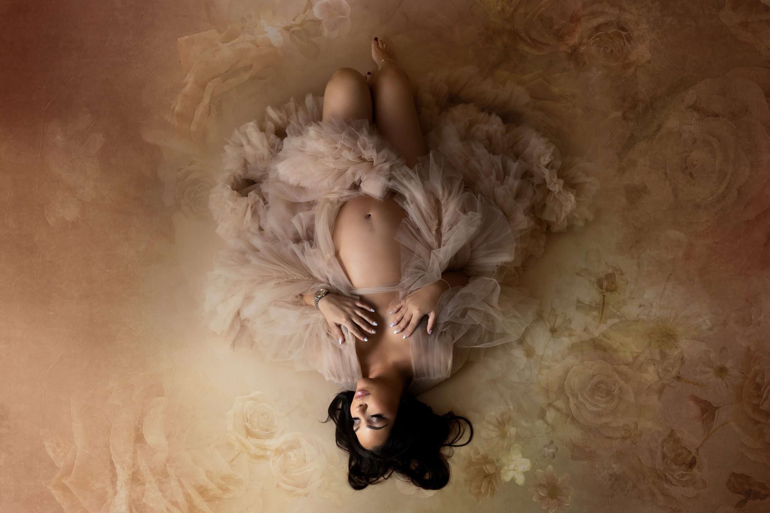 Montreal Maternity Photographer. Photo of a pregnant woman from the top lying down in flowers.