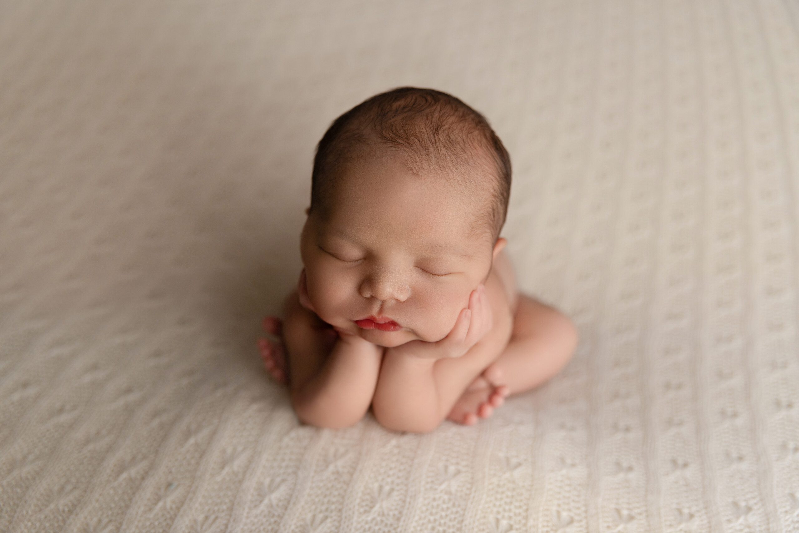 Newborn Photoshoot Montreal. Newborn boy with his hands under his chin.