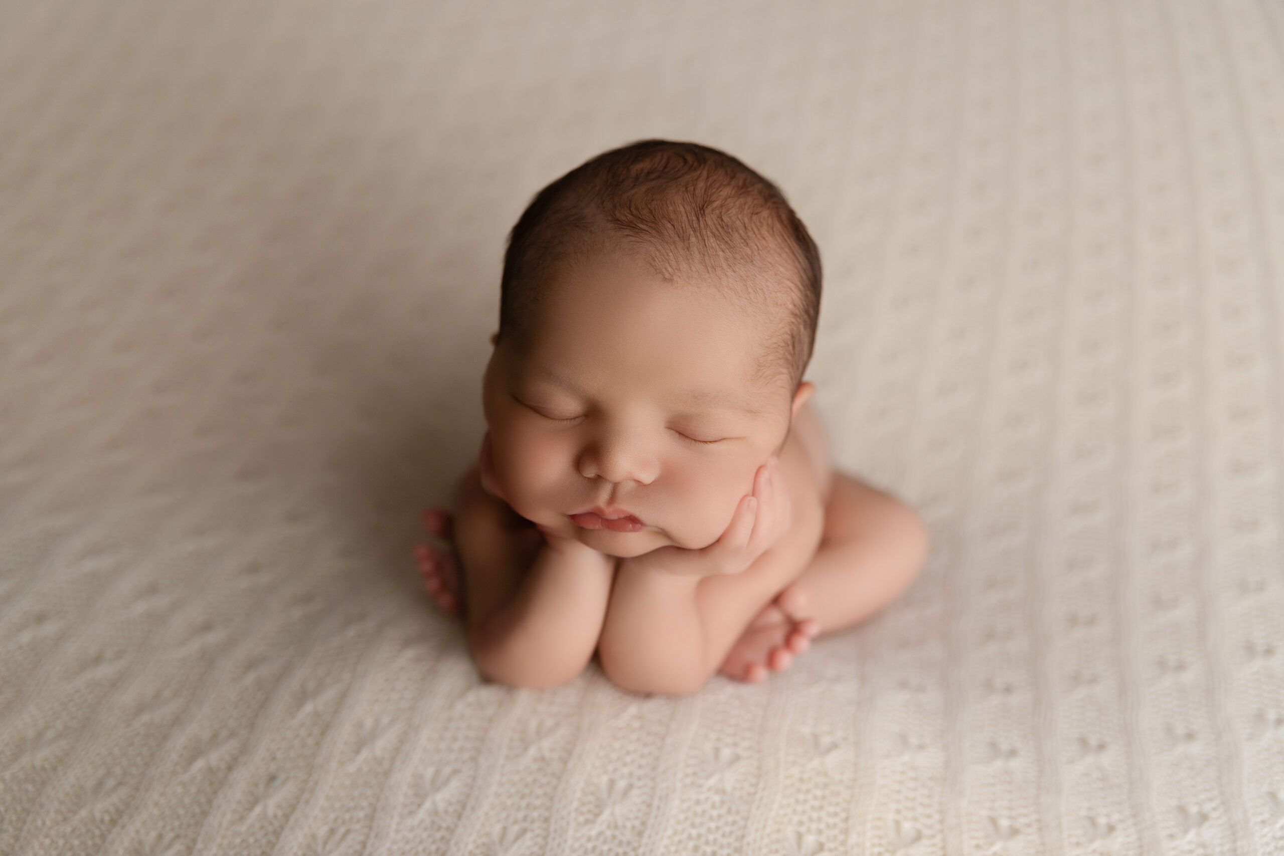 Photo of a newborn baby boy laying on a neutral ivory backdrop by Montreal newborn and maternity photographer